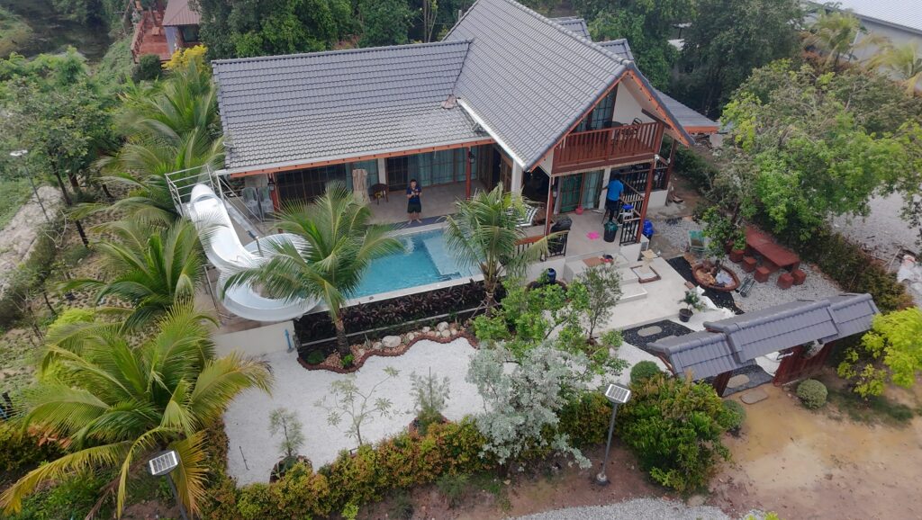 ภาพมุมสูงบ้านพักนาวาฮิลล์ พูลวิลล่านครนายก ท่ามกลางต้นไม้ใหญ่และสระว่ายน้ำส่วนตัว